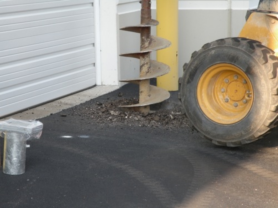 Excavating for bollard installation beside an existing building
