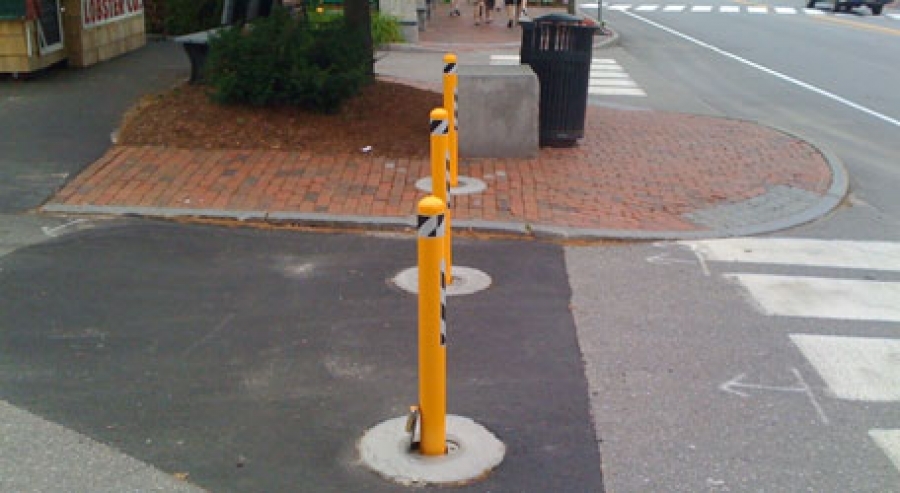 Yellow powder-coated bollards at a crosswalk